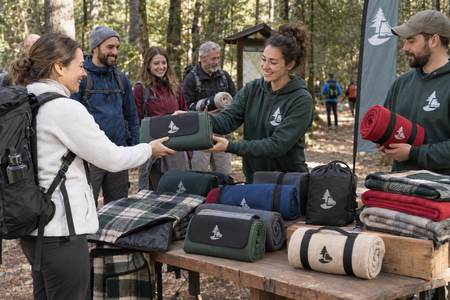 Volontari distribuiscono coperte da campeggio personalizzate durante una camminata nel bosco